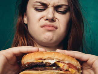 Woman with disgusted looks at the greasy hamburger