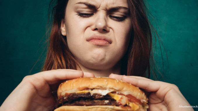080619_03P_FS Woman with disgusted looks at the greasy hamburger