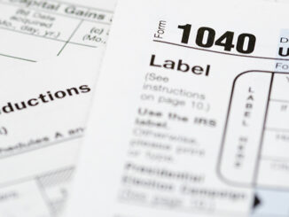 A 1040 tax form with supplemental forms in the background.