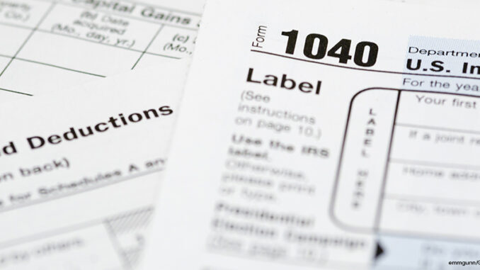Income Tax Form A 1040 tax form with supplemental forms in the background.