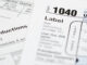 A 1040 tax form with supplemental forms in the background.