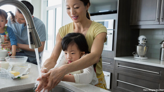 Mother and daughter washing hands in kitchen sink Mother and daughter washing hands in kitchen sink