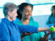 Friendly physical therapist assisting senior patient with strength exercise