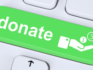 Close-up view of a button on a computer keyboard with the word 'donate' and a hand symbol with coins