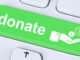 Close-up view of a button on a computer keyboard with the word 'donate' and a hand symbol with coins