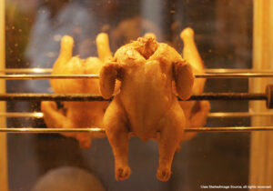 Close-up selective focus view of whole chicken cooking on a rotisserie