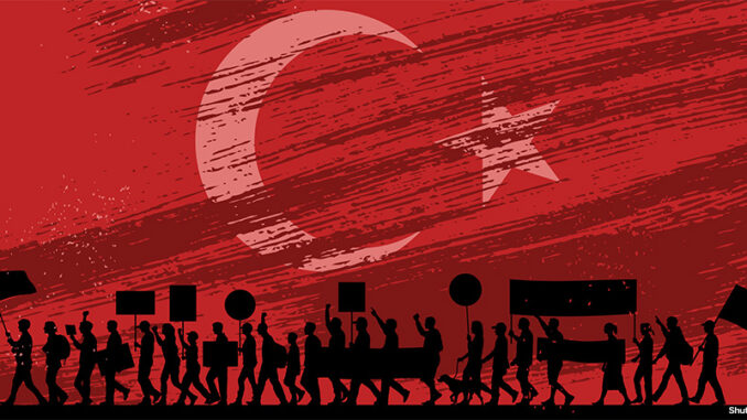 102819_01P_FS silhouetted image of marching protesters with signs in front of a full background image of the Turkey national flag