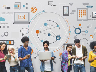 group of multicultural men and women on digital devices in front of a wall of digital images and computer-based icons