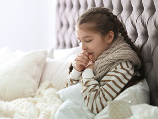 Sick little girl with cough suffering from cold in bed