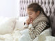 Sick little girl with cough suffering from cold in bed