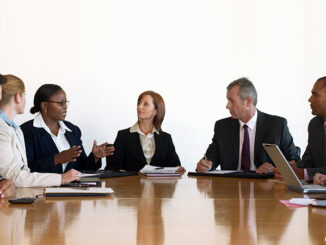 Business men and business women in meeting around conference table.