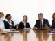 Business men and business women in meeting around conference table.