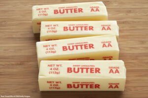 Elevated view of four quarter pound sticks of sweet unsalted AA grade butter on a bamboo cutting board