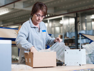Female warehouse worker packing box for conveyor belt