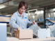 Female warehouse worker packing box for conveyor belt