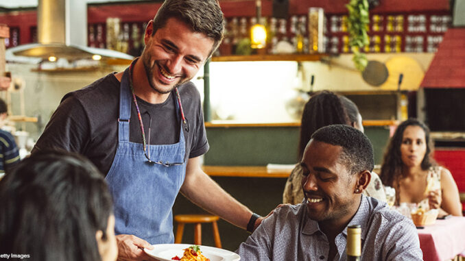 Cheerful male chef serving couple in restaurant and smiling Cheerful male chef serving couple in restaurant