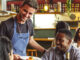 Cheerful male chef serving couple in restaurant