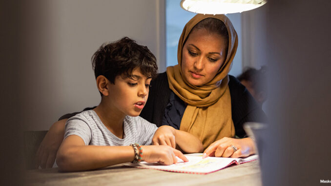 Mother and son reading book in darkroom at home Mother and son reading at home