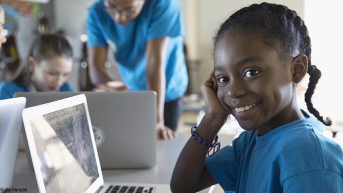Portrait confident, smiling pre-adolescent girl using laptop in classroom children learning in school setting