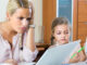 Tired woman irritated as her preschooler daughter diverts her from work at home