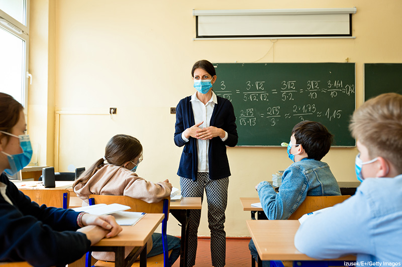 teacher and students wearing masks in school classroom