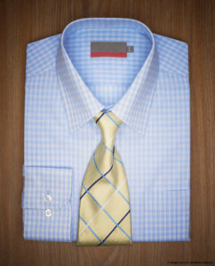 man's folded blue and white checked dress shirt and yellow necktie