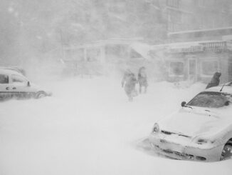 Street scene of a winter blizzard with people walking about in a city