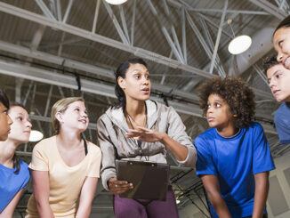 Group of children with coach in school gym