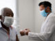 Portrait of African American male patient getting vaccination using face mask