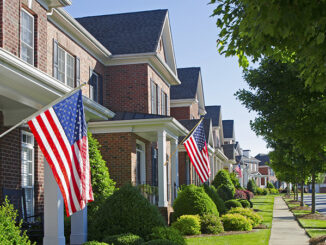 American Flags hang from the front of this traditional, brick homes