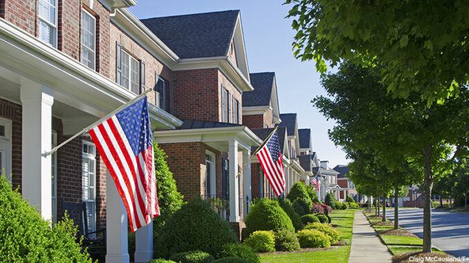 American Flags hang from the front of this traditional, brick homes