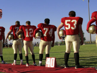 a football team standing for the American National Anthem