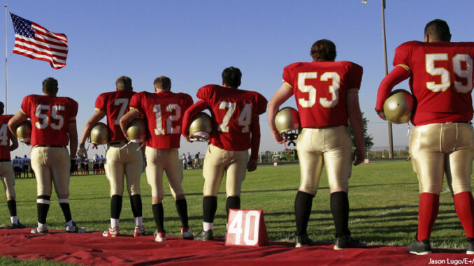 Sports - Football a football team standing for the American National Anthem