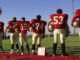 a football team standing for the American National Anthem