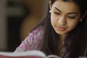 photograph of a young woman reading an open book