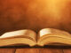 image of open book on wooden table with glitter background;