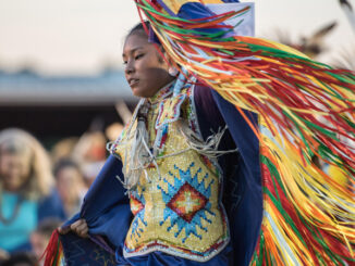 Native American woman performing grass dance in traditional attire