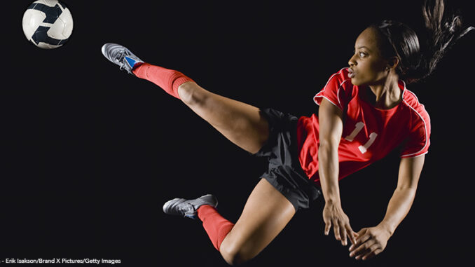 Mixed race soccer player kicking soccer ball in mid-air soccer player kicking soccer ball in mid-air