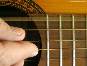 close up of acoustic guitar with oscillating E-string