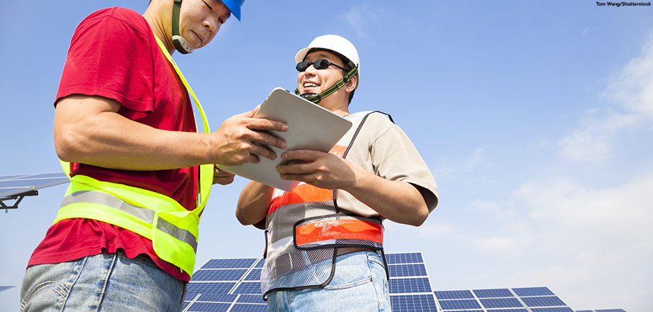 two workers discussing with tablet pc before solar power station