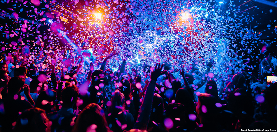 silhouettes of concert crowd in front of bright stage lights and confeti;