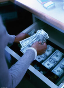 photo of a bank teller removing money from an open cash drawer