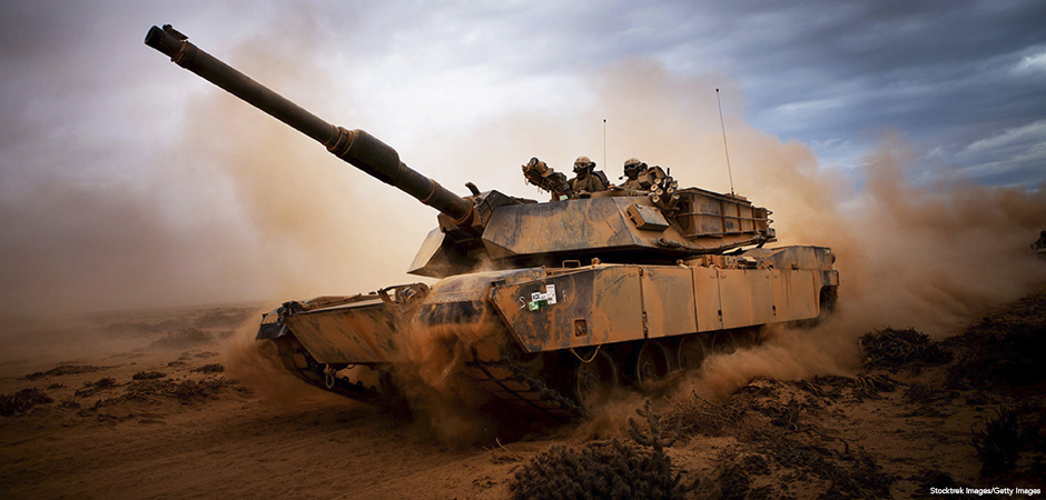 Marines roll down a dirt road on their M1A1 Abrams Main Battle Tank