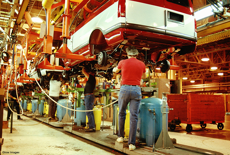 workers assembling vehicle on suspended assembly line