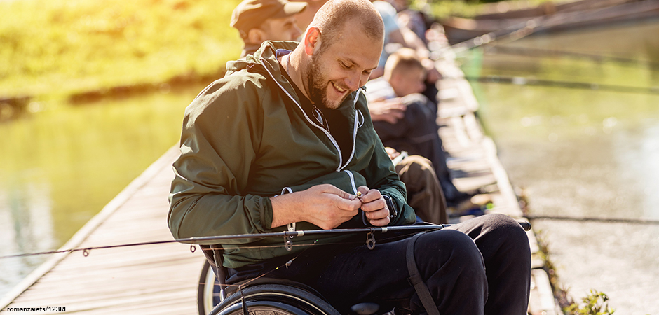 A person with a disability, sitting in a wheelchair, enjoys some fishing.