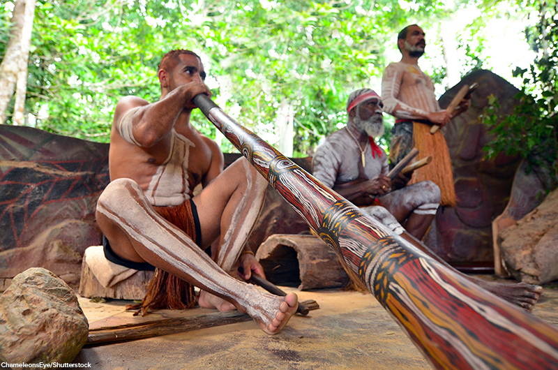 three Yirrganydji Australian aborigines playing musical instruments including didgeridoo during an Aboriginal culture show in Queensland, Australia
