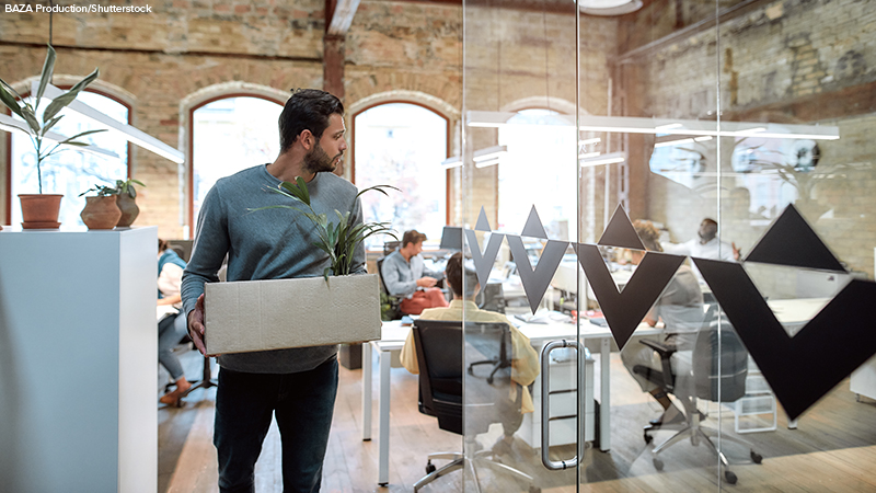 man in casual wear holding box with personal things and leaving modern office