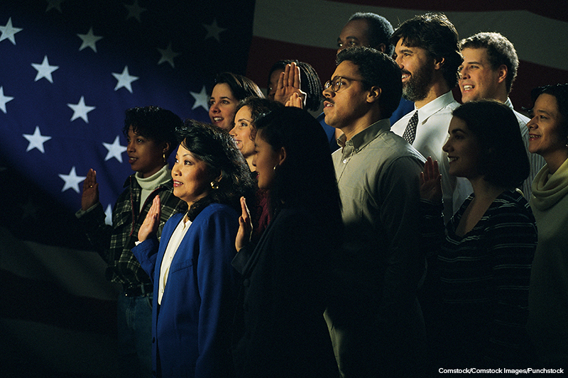 immigrants taking a pledge with an American flag in the background