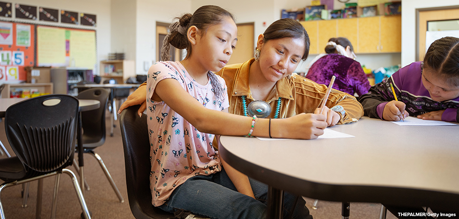 Indigenous teacher and student in a classroom.