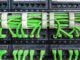 Server rack with green internet patch cord cables connected to patch panel in server room